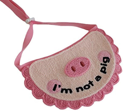 Pink crocheted pet saliva towel with pig face and 'i'm not a pig' text patch