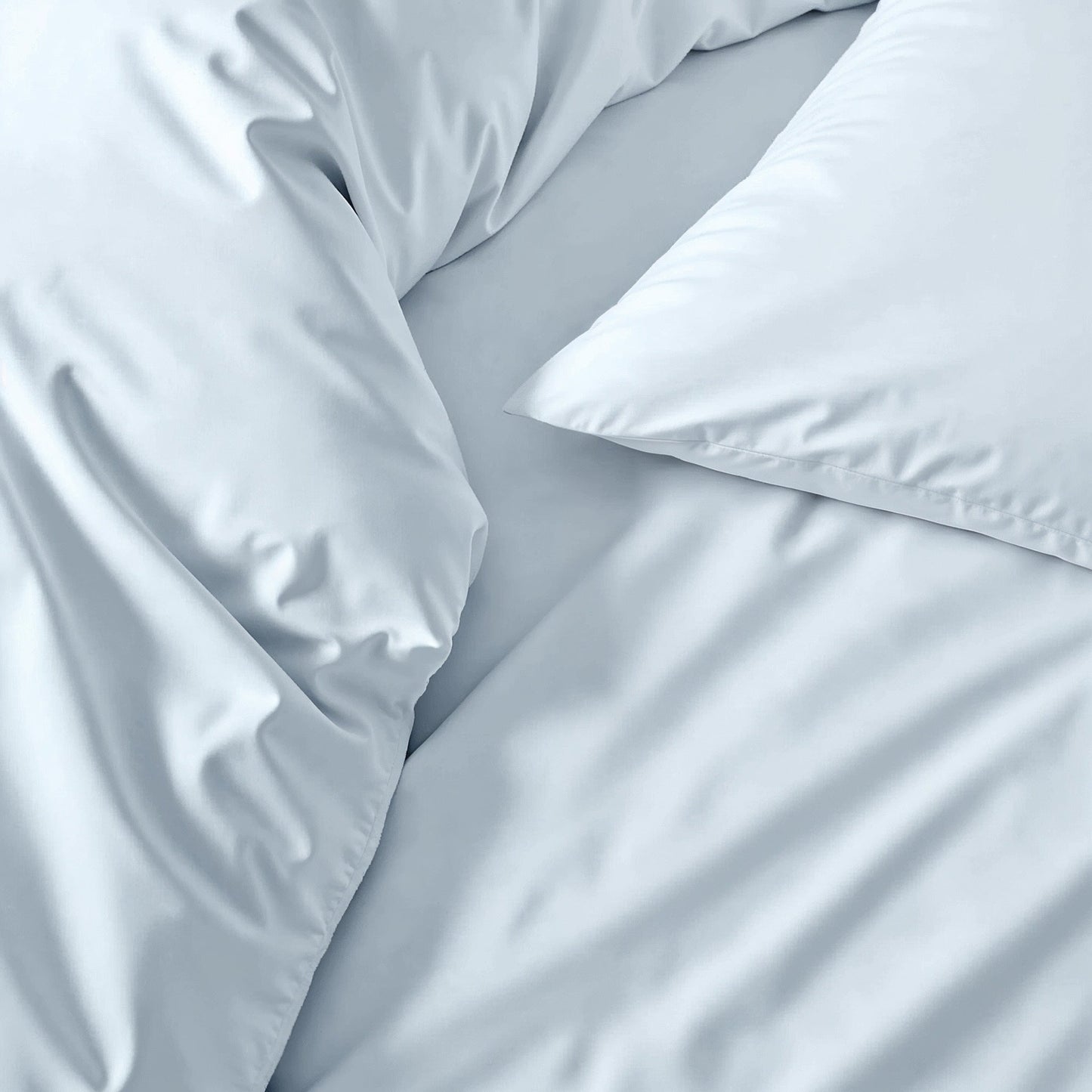Sateen sheet set in light blue-gray, close-up of smooth bedding fabric