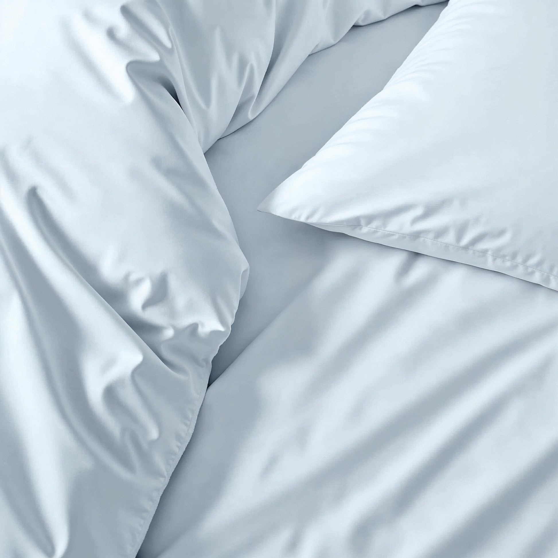 Sateen sheet set in light blue-gray, close-up of smooth bedding fabric