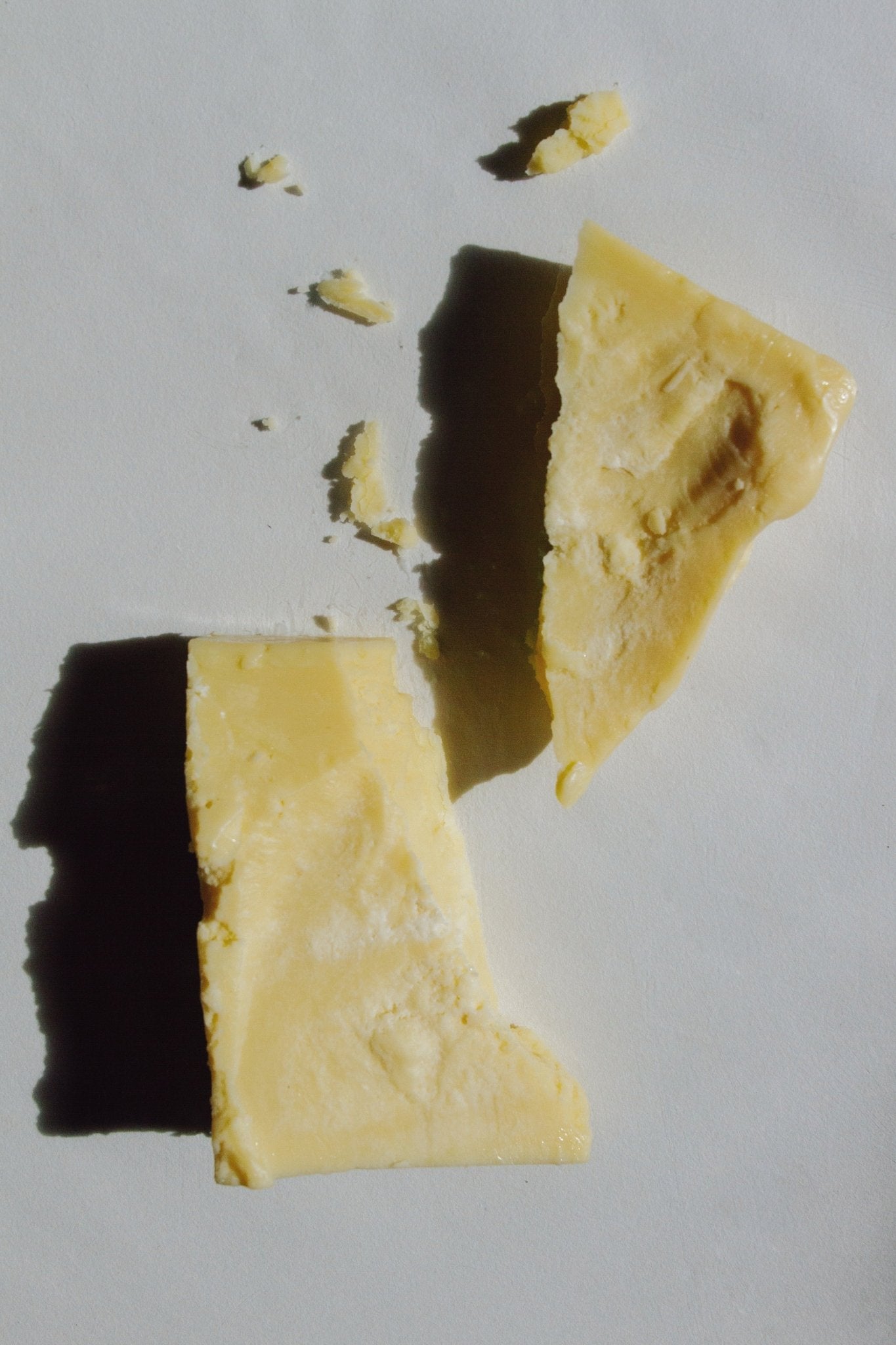 Pale yellow cacao butter chunks with broken edges and small flakes