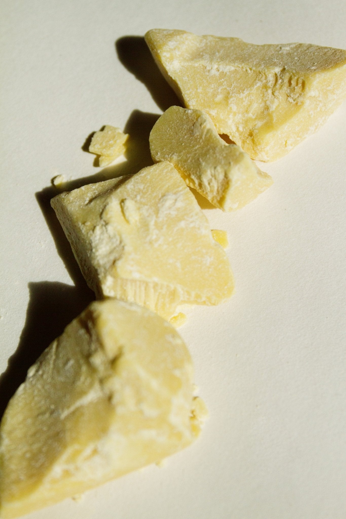 Raw cacao butter chunks, pale yellow pieces with crumbly texture