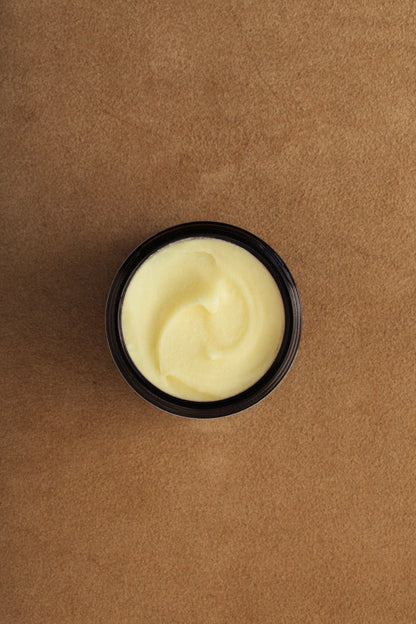 Open balm jar with smooth creamy yellow balm, black rim