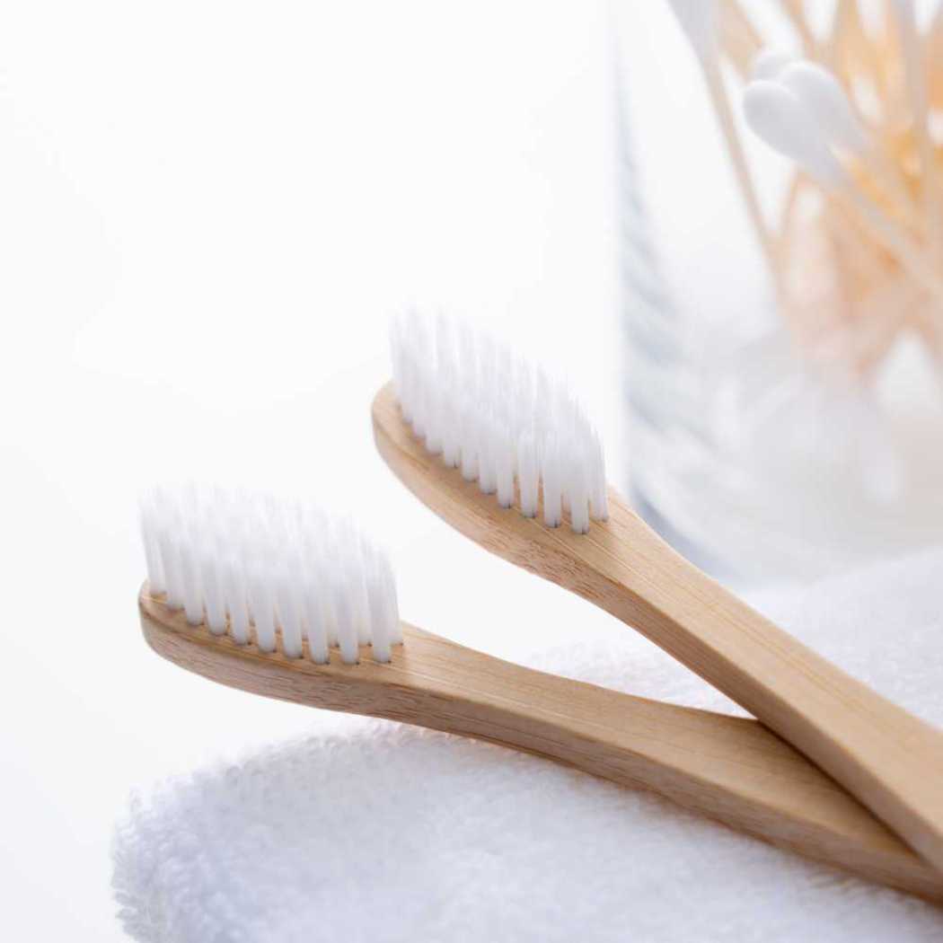 Bamboo toothbrush pair with curved light wood handles and white bristle heads