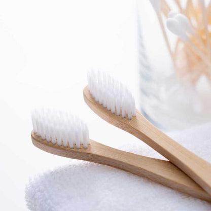 Bamboo toothbrush pair with curved light wood handles and white bristle heads