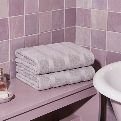 Lilac cotton towels folded and stacked with striped bands
