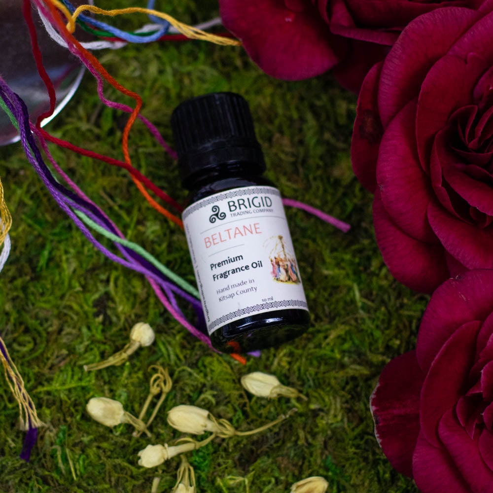 Essential oil blend bottle Beltane with black cap on grass and flowers