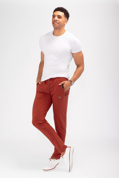 Tapered athletic sweatpants in rust red, elastic waistband with drawstring, cuffed ankle hems.