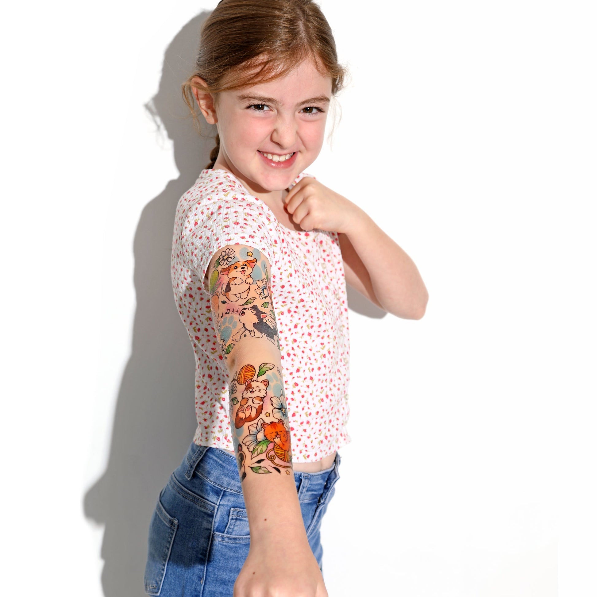 Kids temporary tattoo sleeve on child’s arm with cartoon dog and orange cat