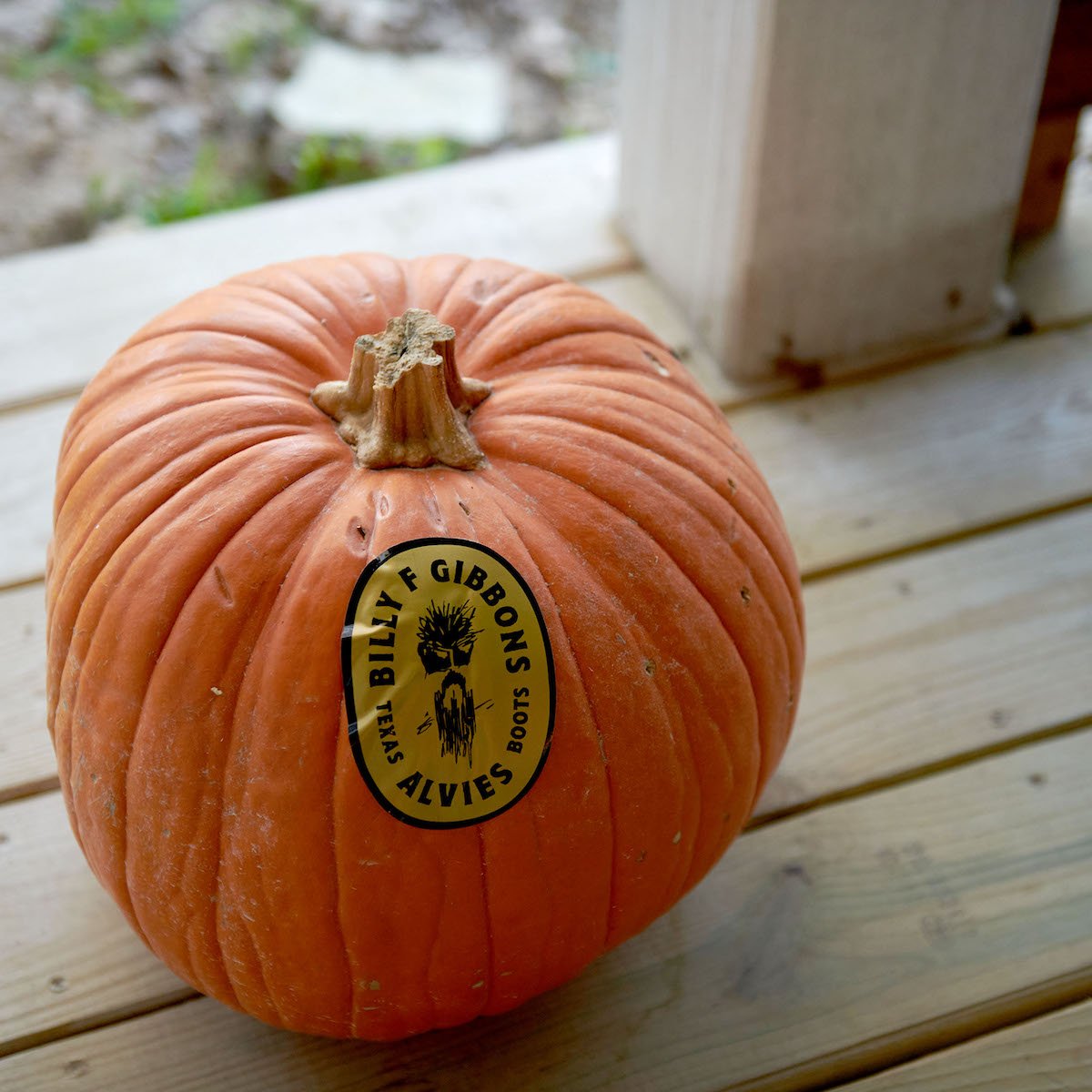 Round sticker with black logo and text on orange pumpkin