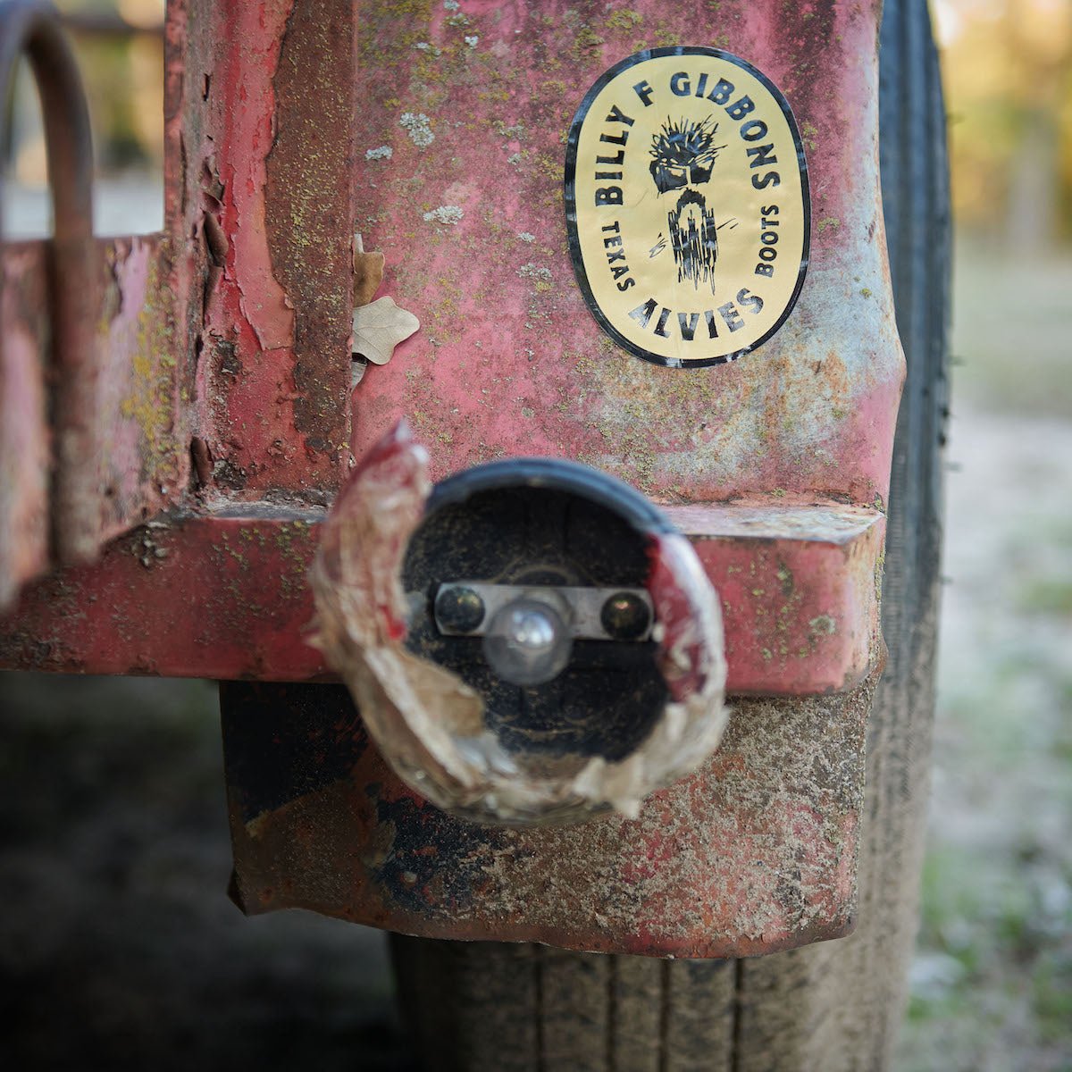 Round sticker with black logo and text on rust-red metal panel