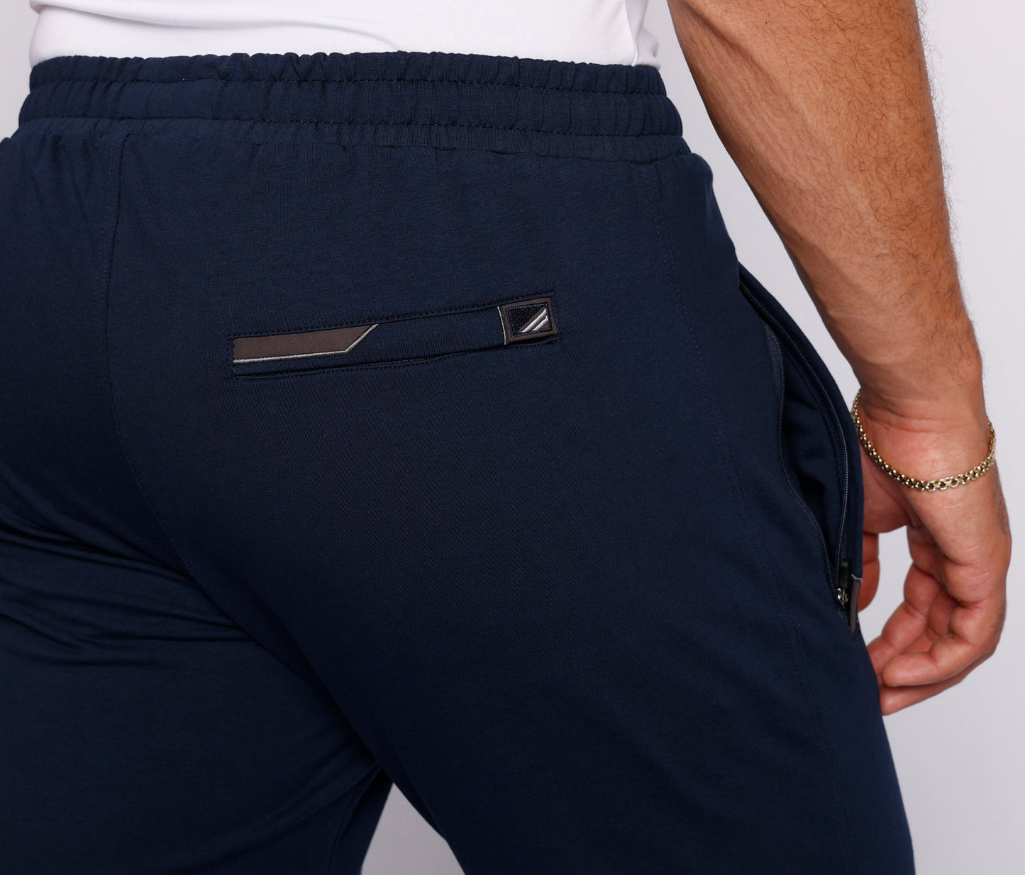 Navy athletic sweatpants back view with elastic waistband and logo patch pocket