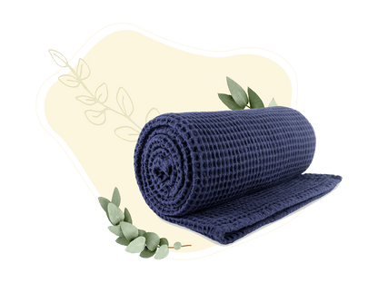 Deep blue waffle weave throw blanket rolled and folded, showing waffle texture.