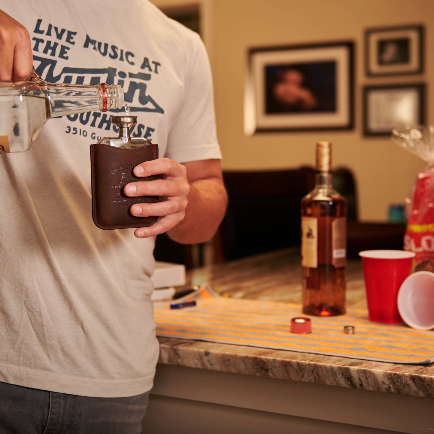 Brown boot flask with silver cap held in one hand.
