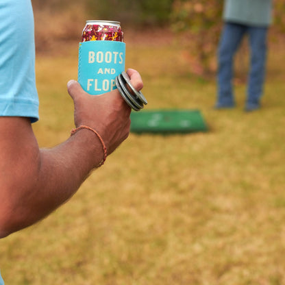Blue can cooler sleeve on a soda can held in hand