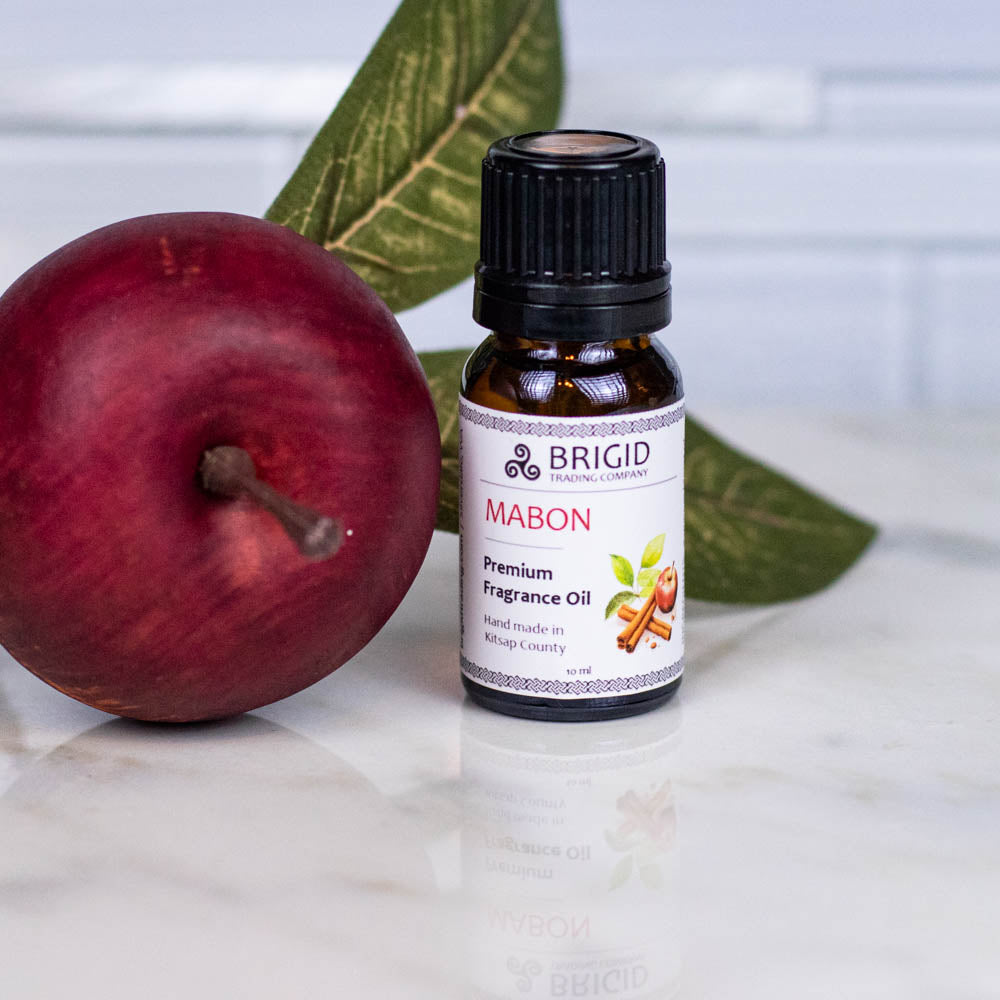 Diffuser oil bottle with black cap and label, beside a red apple and green leaf