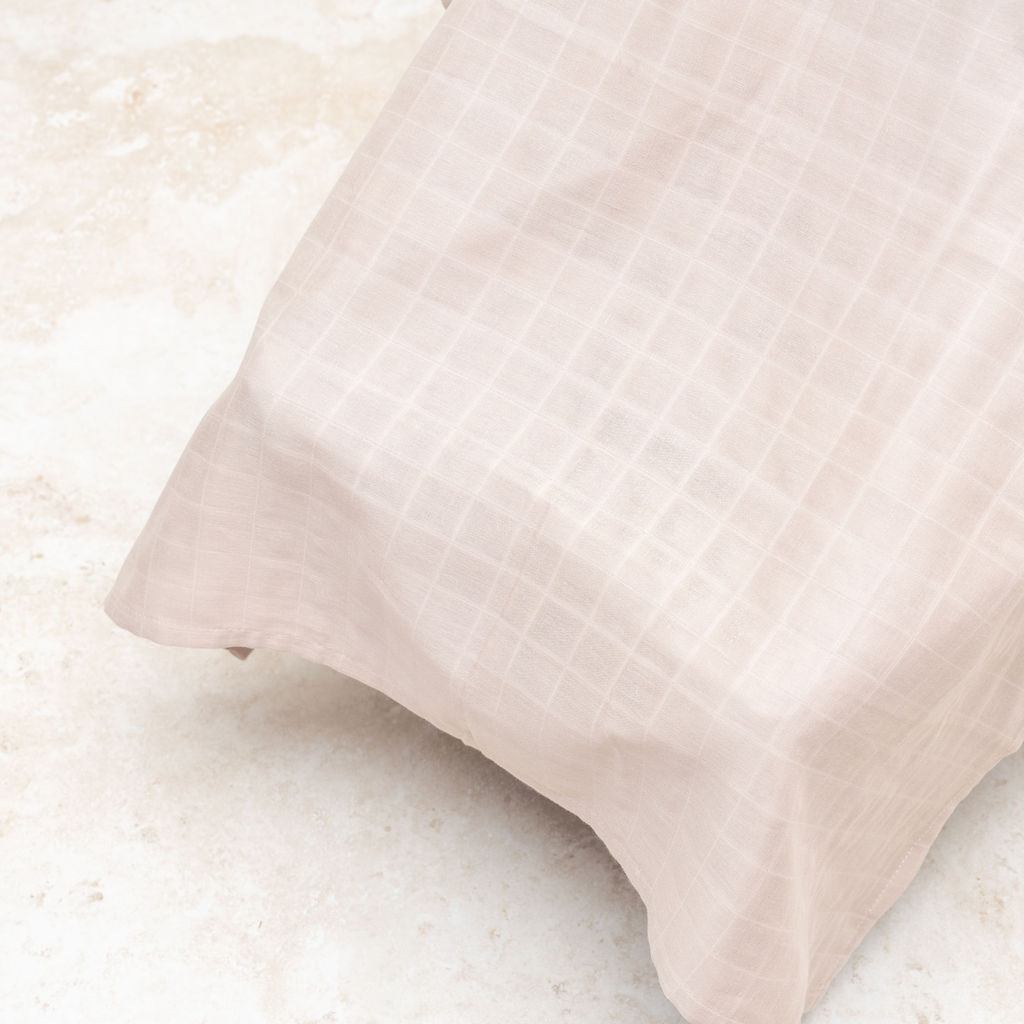 White muslin car seat cover fabric with checkered weave and stitched corner hem