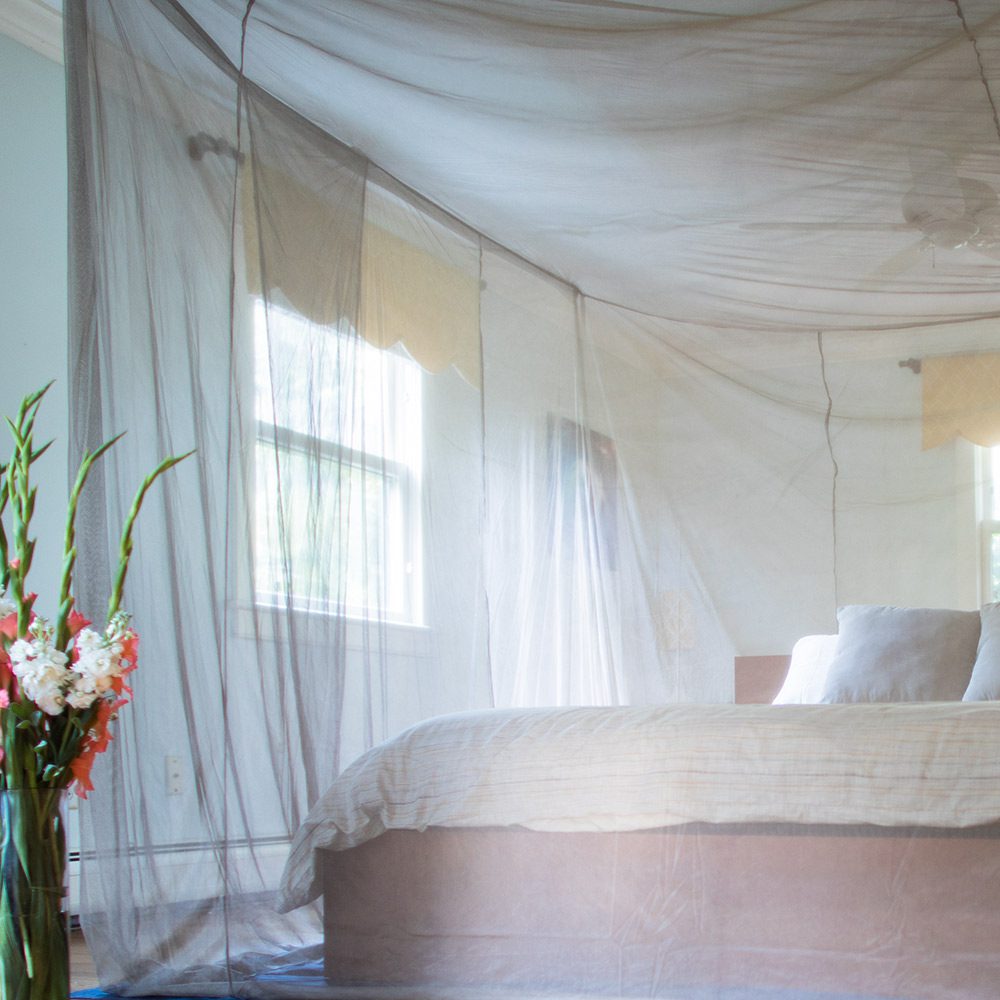 EMF shielding bed canopy with sheer draped fabric over a bed