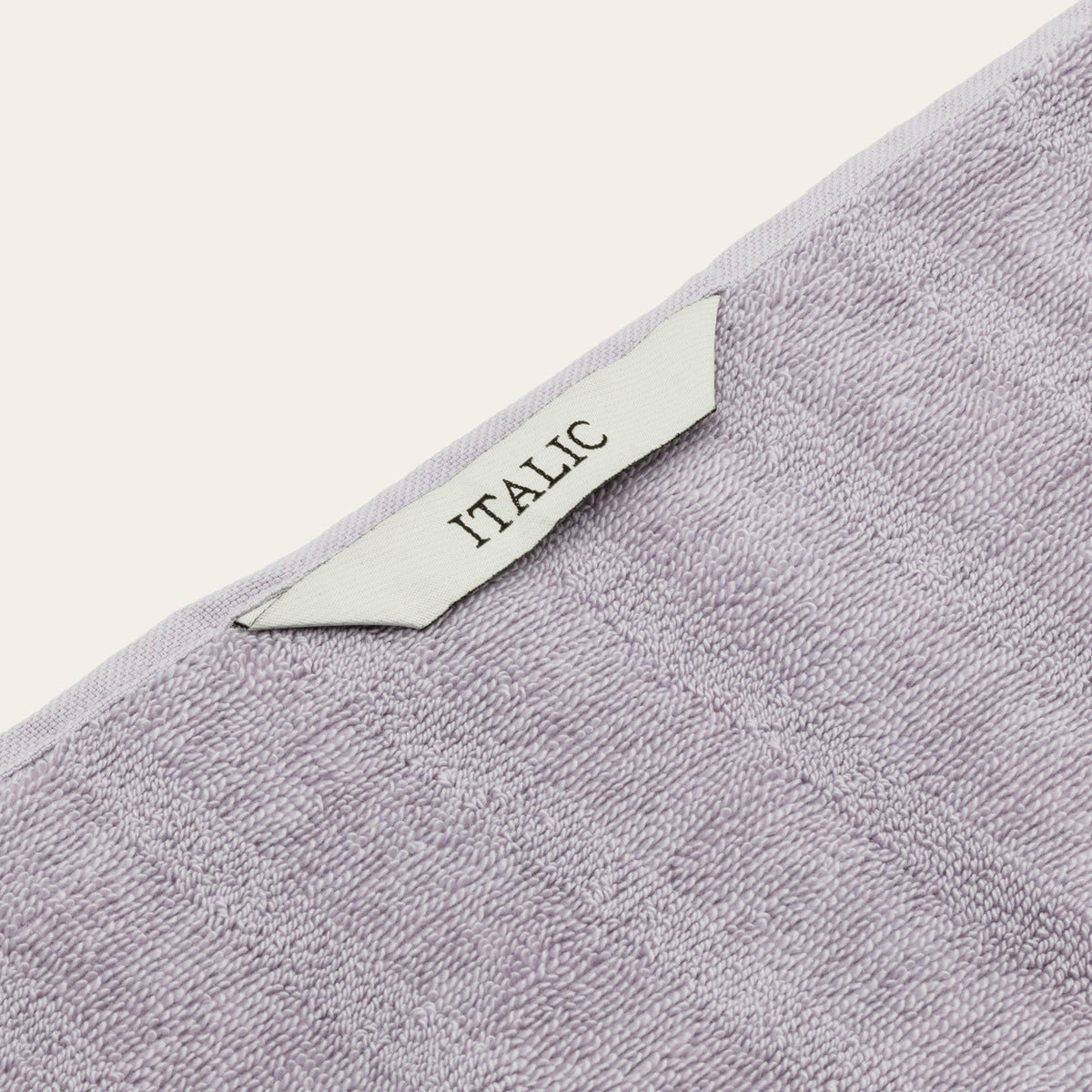 Lilac cotton towel corner with decorative trim and “ITALIC” label