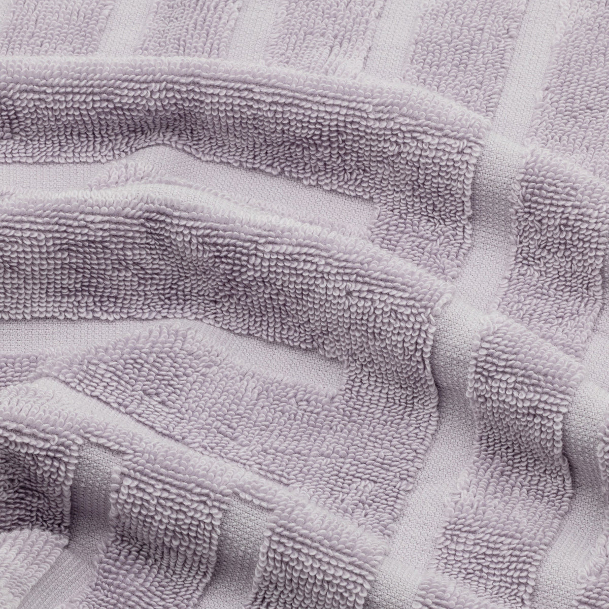 Lilac cotton towel fabric close-up with terry texture and striped pattern