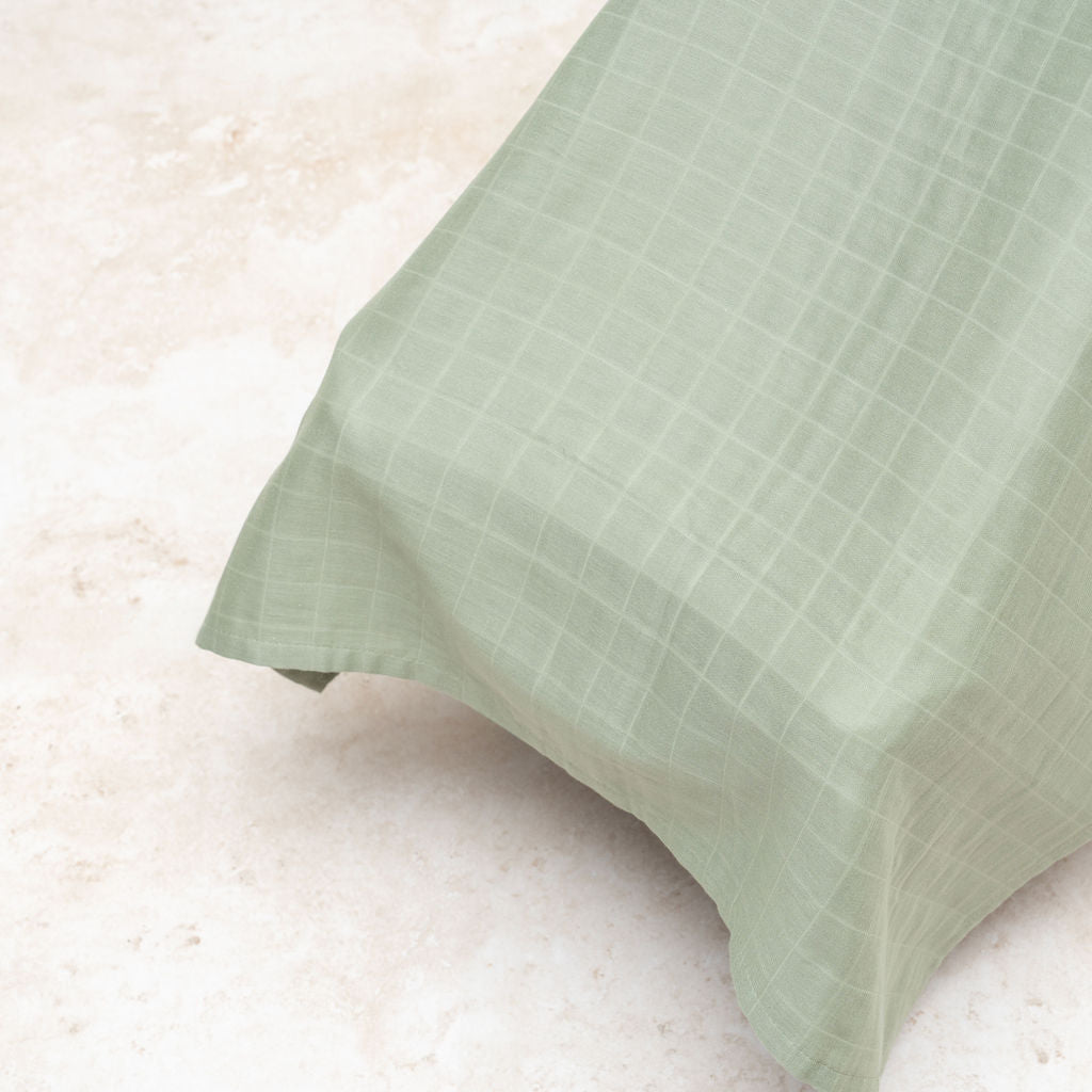 Green muslin car seat cover fabric panel with checkered texture and stitched hem