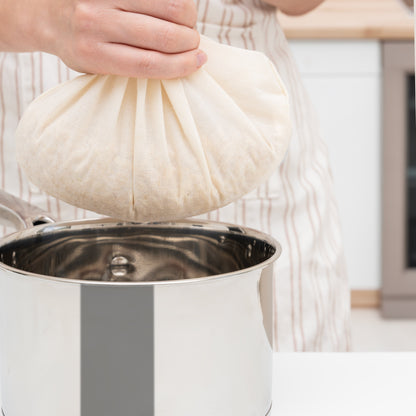 Nut milk bag being lifted, off-white mesh pouch with drawstring opening
