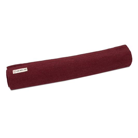 Organic cotton yoga mat, maroon rolled with fabric label at side.