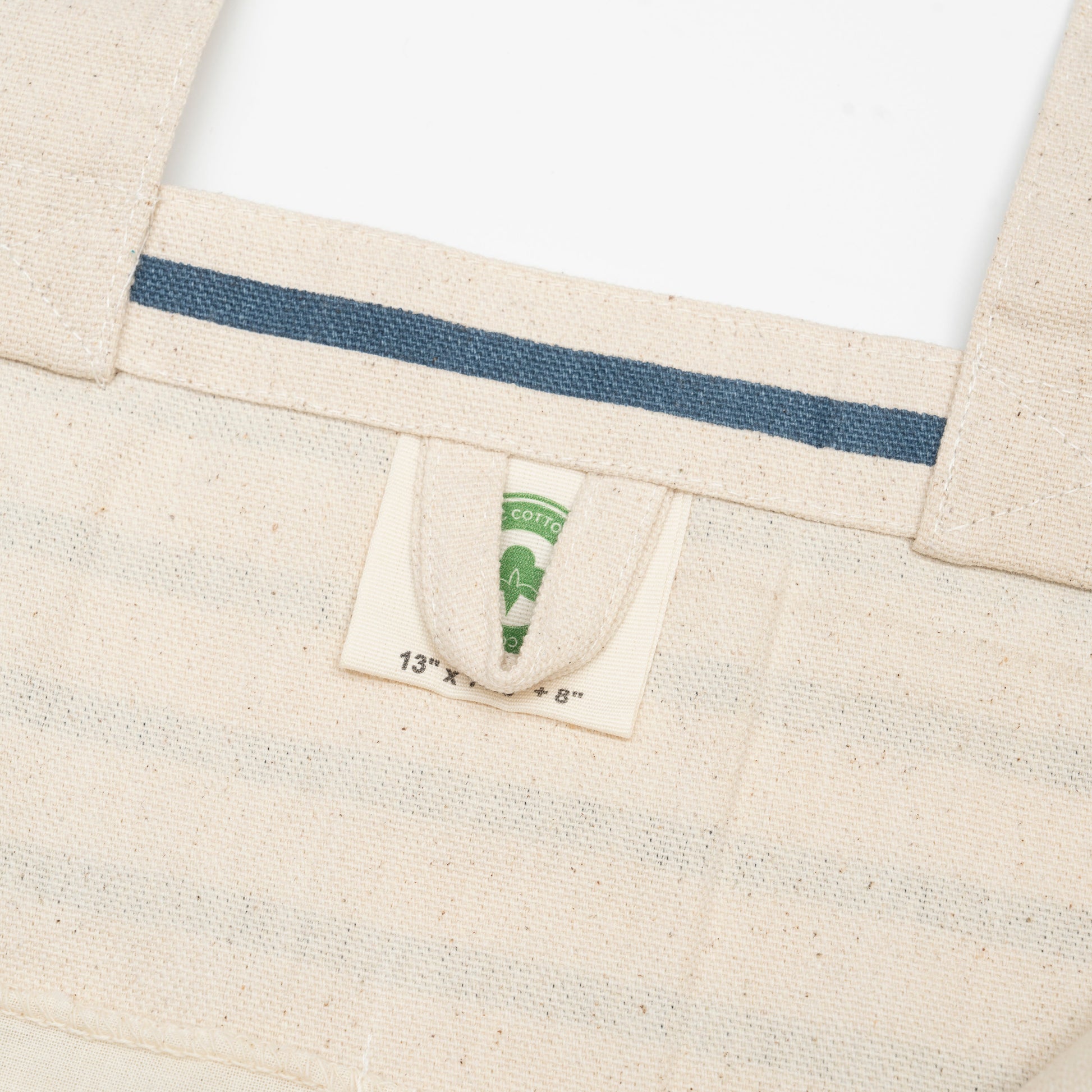 Canvas grocery tote bag label detail, beige canvas with blue stripe and inner tag
