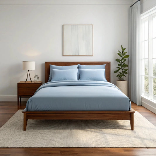 Dusty blue sheet set with two pillowcases and fitted-style top cover on a bed