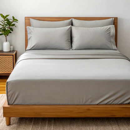 Powder white sheet set with two pillowcases and duvet cover on a bed.