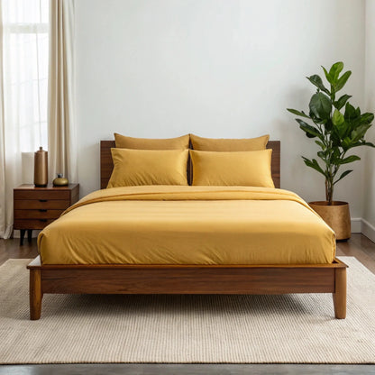 Mustard yellow sheet set with two pillowcases on a bed.