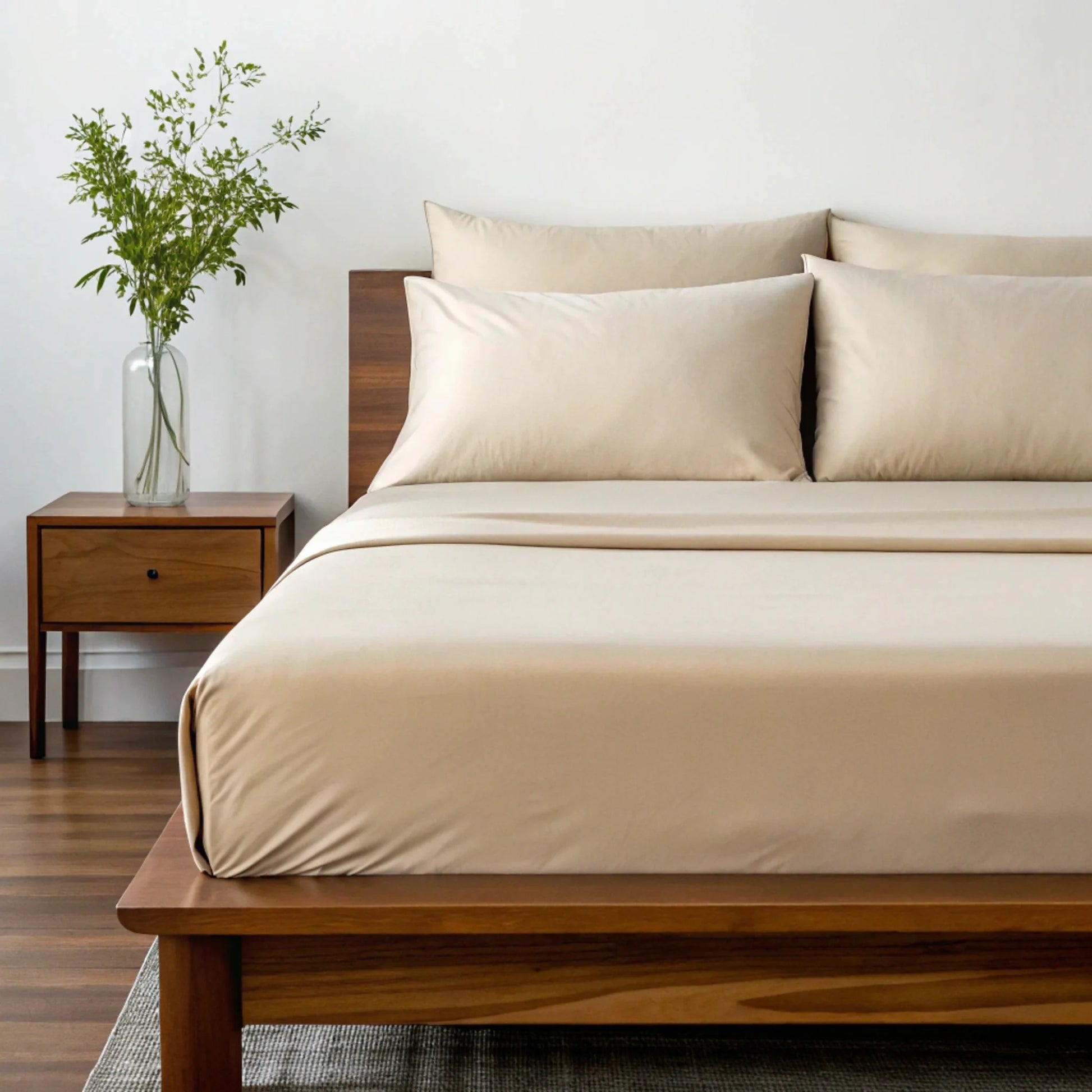 Beige sheet set with two pillows and duvet cover on wooden bed frame.