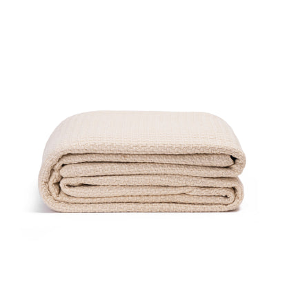 Beige basket-weave blanket neatly rolled with stacked layers