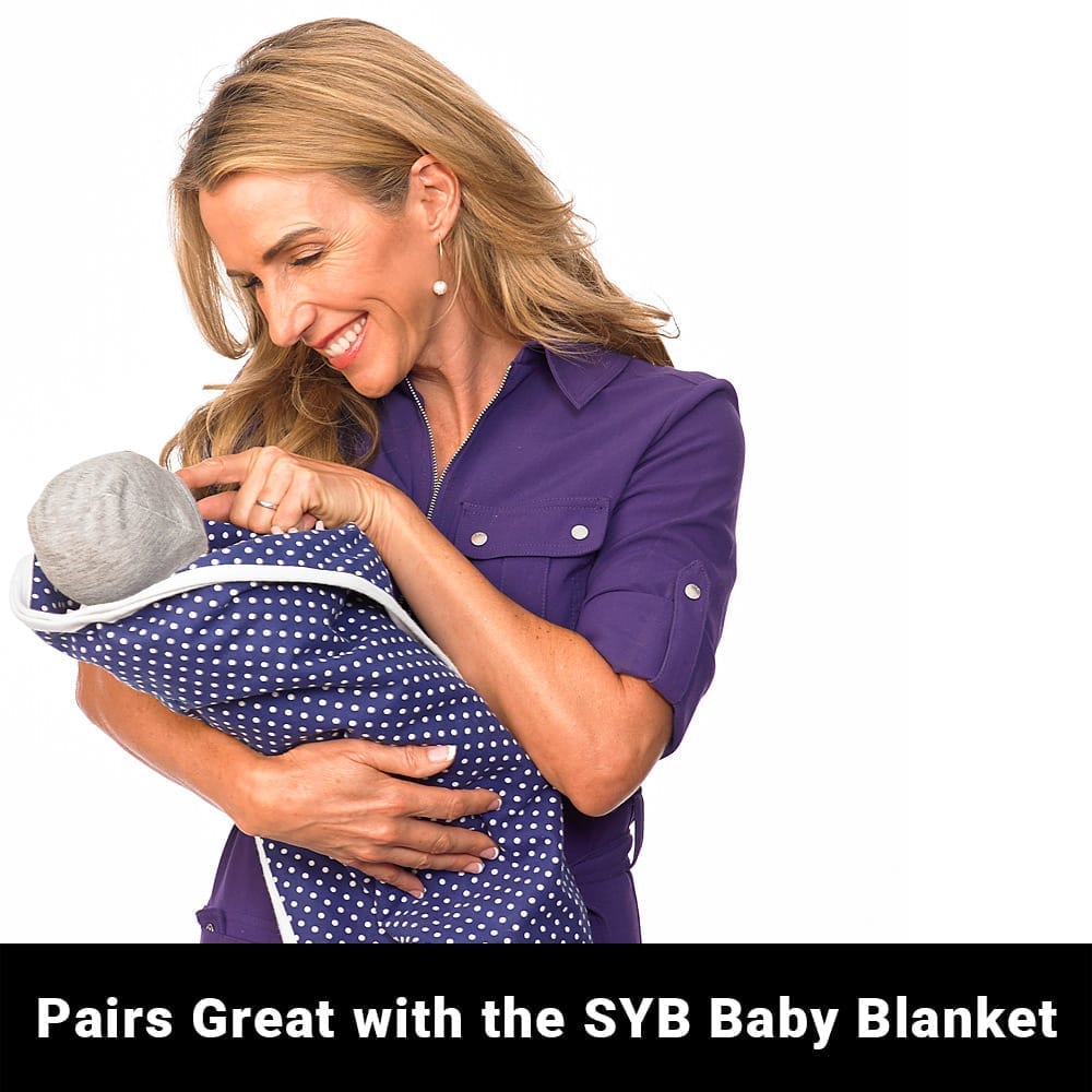 Gray baby beanie worn by baby in blue polka dot blanket