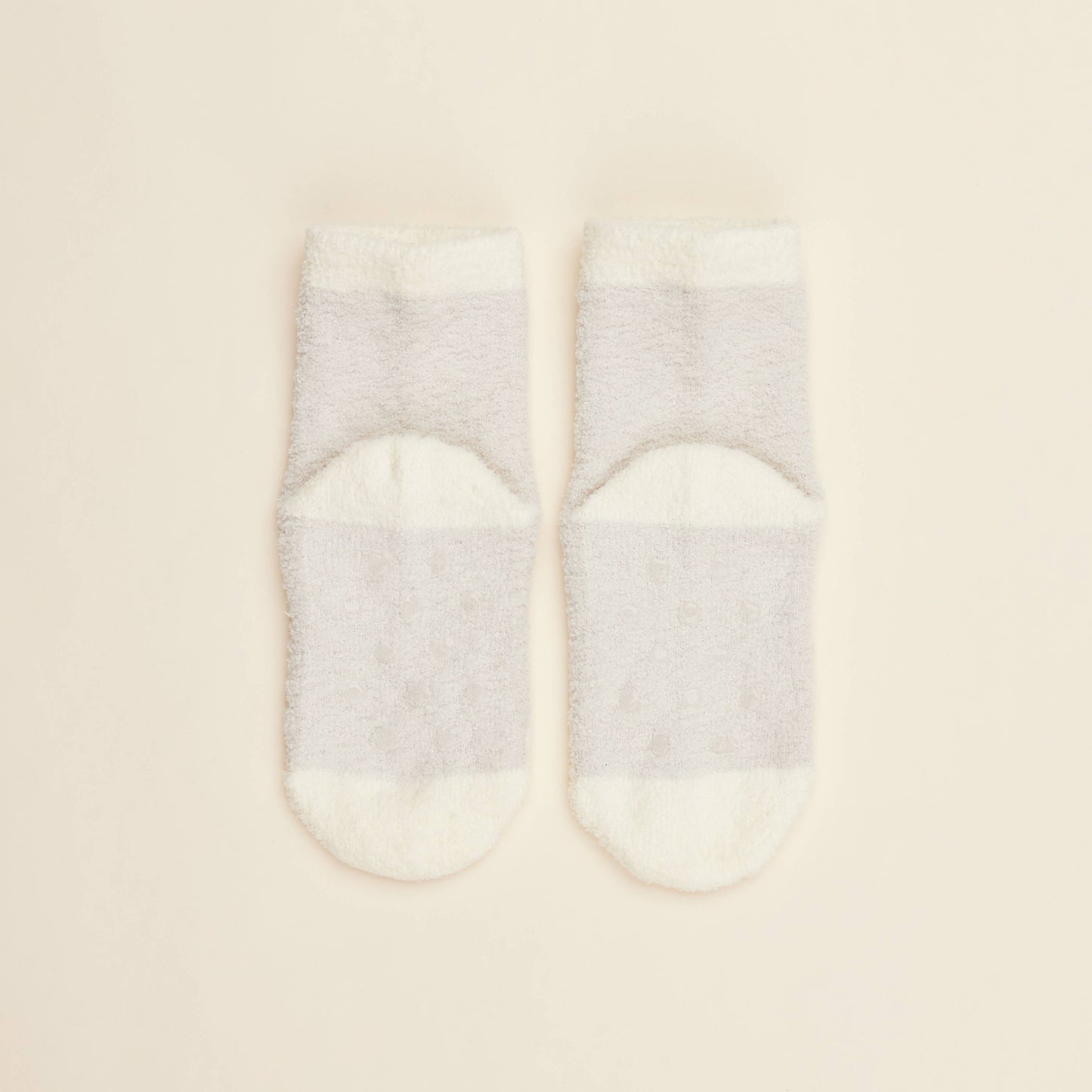 Two cream crew socks with solid design and small heart pattern near toe