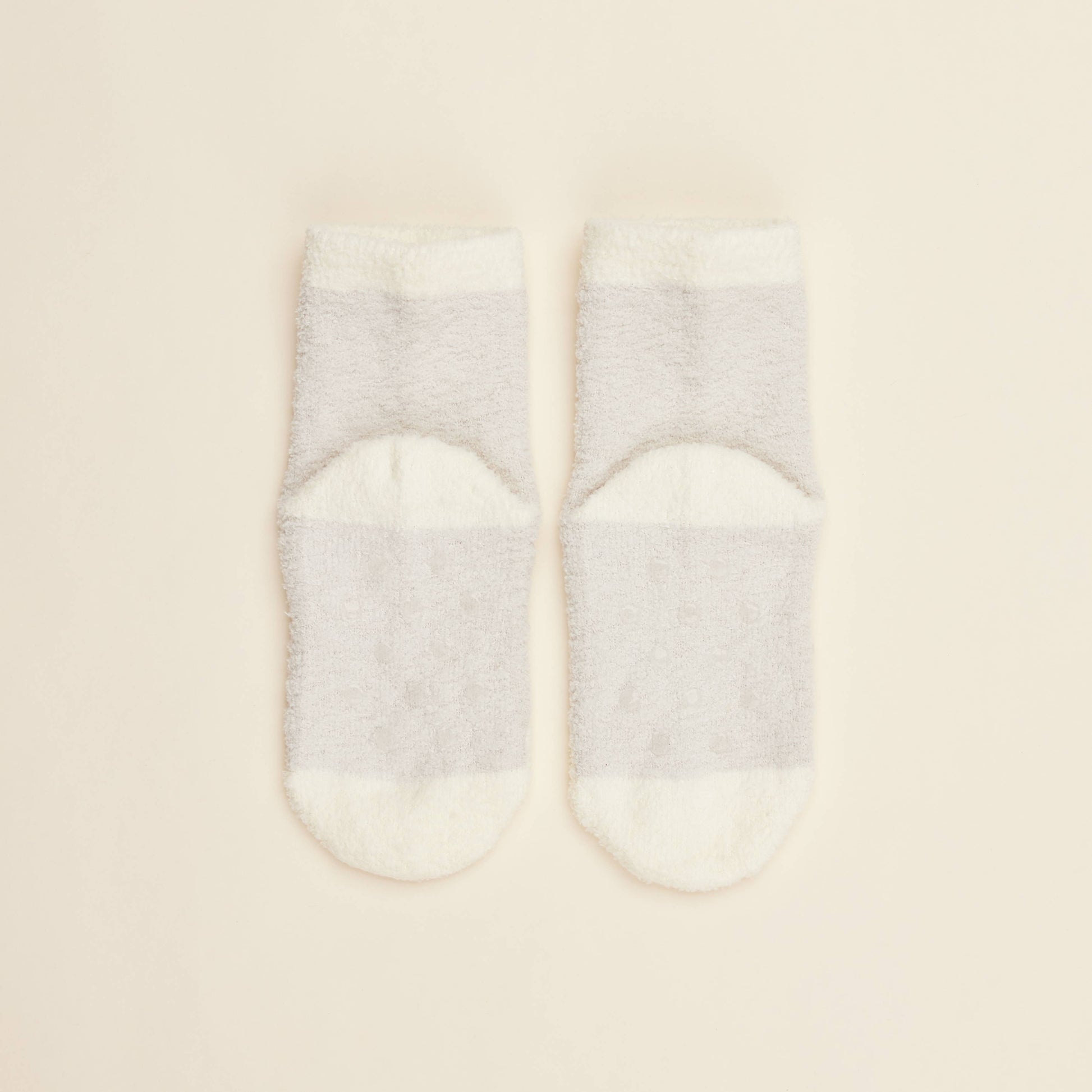 Two cream crew socks with solid design and small heart pattern near toe