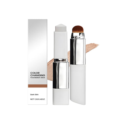 Color-changing foundation stick with brush tip and beige swatch, dark skin tone