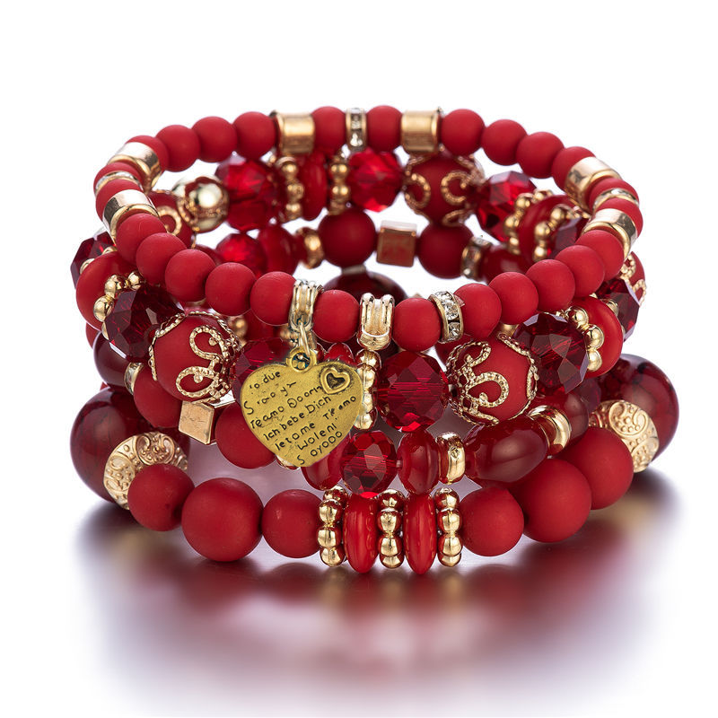 Layered charm bracelet set with red beads, gold links, and heart pendant in front