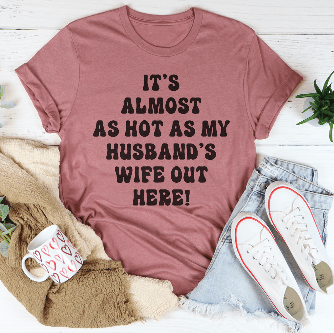 Mauve graphic T-shirt with 'It's almost as hot as my husband's wife out here!'
