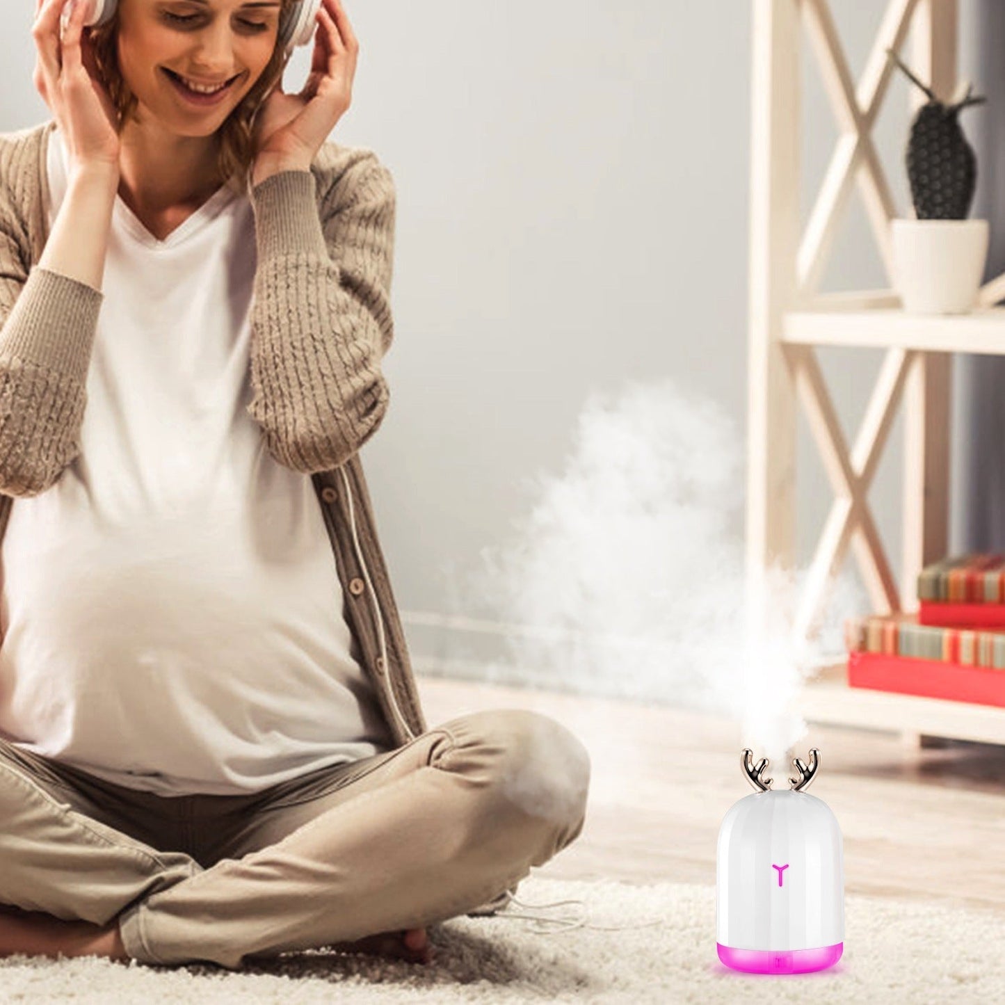 White cool mist humidifier with pink-lit base releasing mist in living room