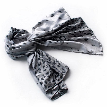 Silver silk scarf with black leopard print, tied in a loose knot