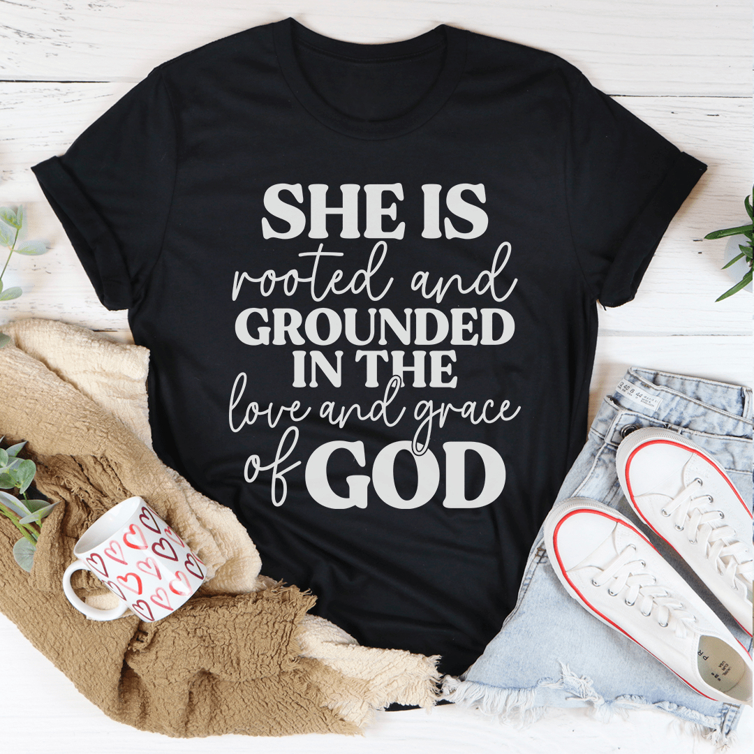Black crewneck faith T-shirt with white 'SHE IS rooted and grounded...' text