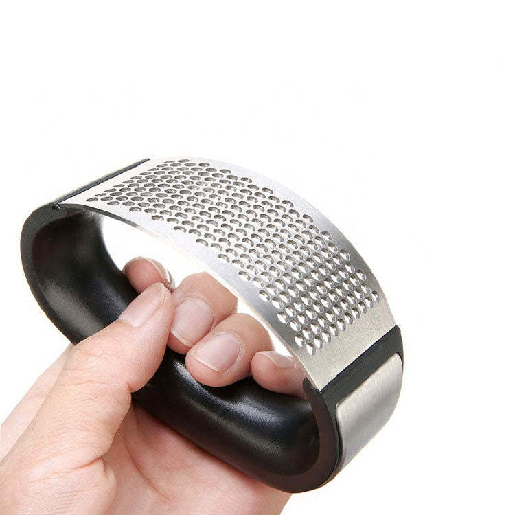 Garlic press head with perforated stainless steel plate, held in hand with black handle