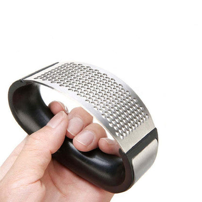 Garlic press head with perforated stainless steel plate, held in hand with black handle