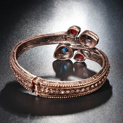Rose-gold tone bangle with small red and blue stones and beaded CZ edge detail