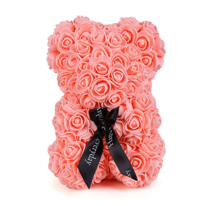 Pink rose teddy bear with layered rose petals and a black ribbon bow at the front