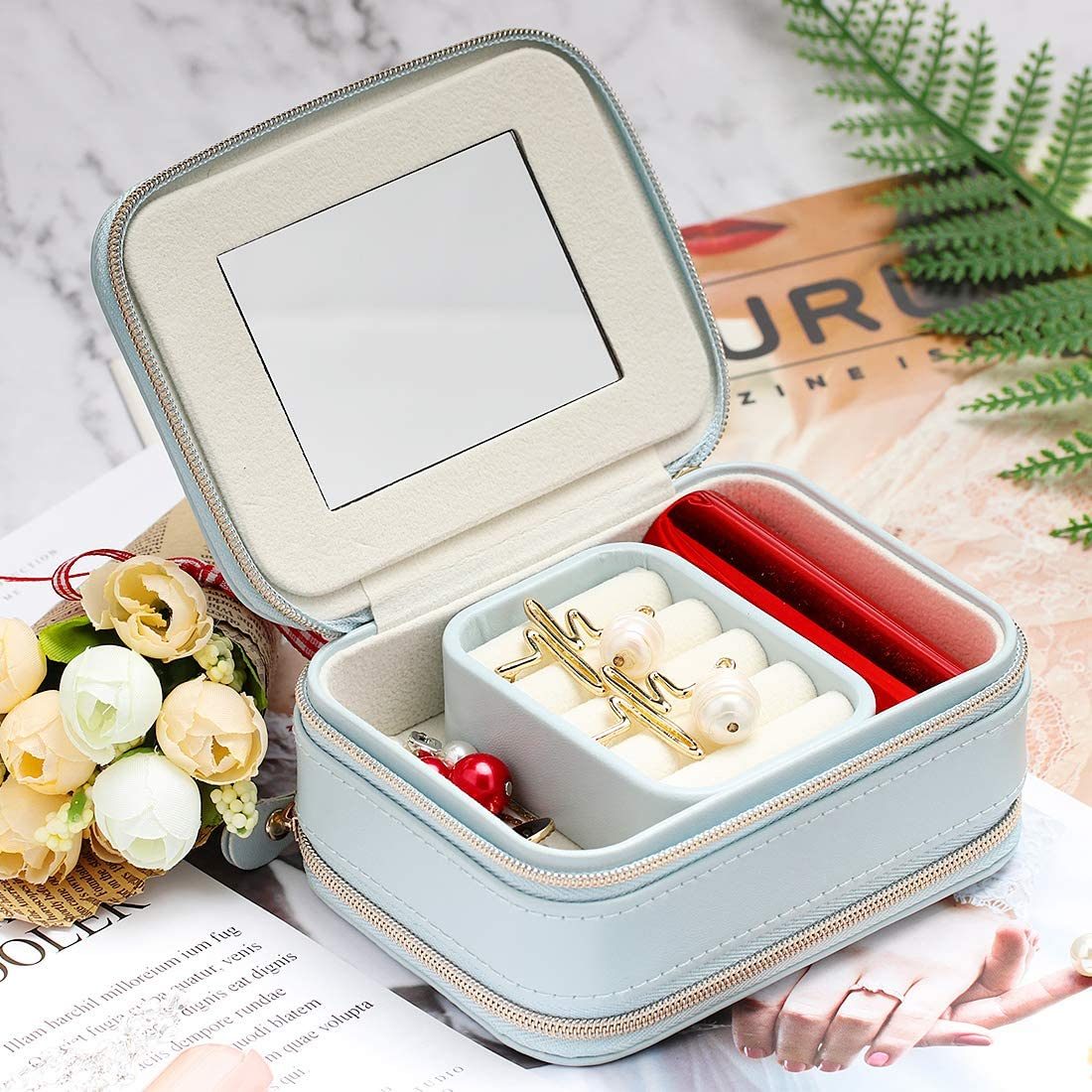Light blue jewelry organizer case open with ring slots and a red inner tray compartment