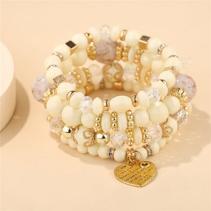 Layered beaded charm bracelet set with cream beads, gold-tone links, and heart pendant
