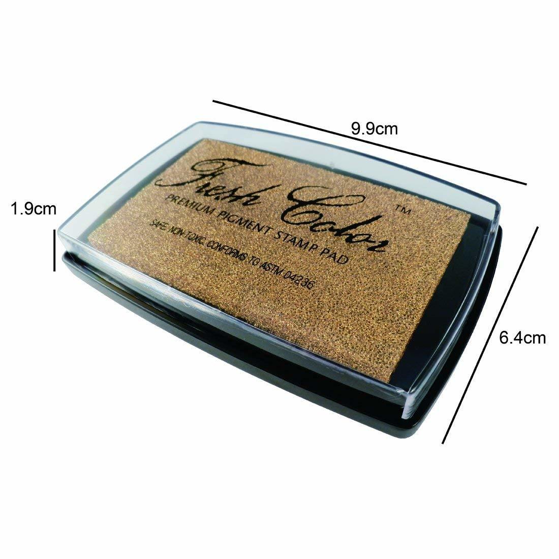 Gold pigment stamp pad top view in clear lid, black base, speckled ink surface.