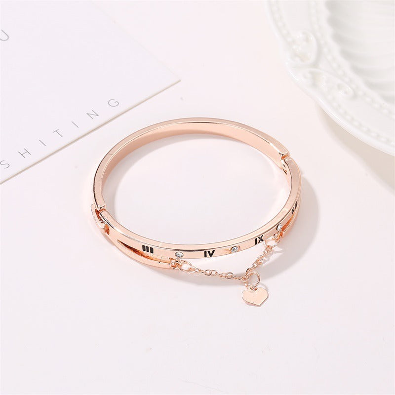 Gold stainless steel bangle bracelet with Roman numerals, small stones, heart charm