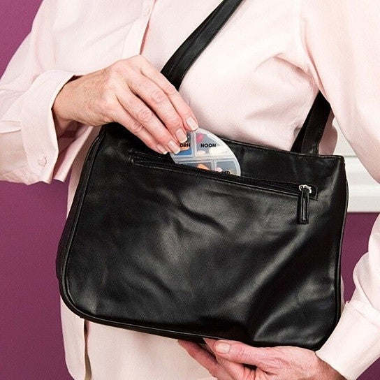 Black zippered medicine case holding a 7-day pill organizer insert